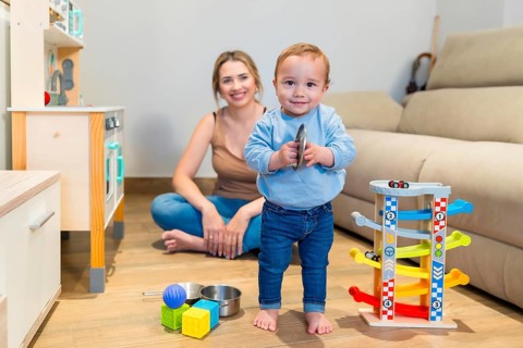Adorable baby boy playing with a toy cymbal while mother sits on the floor, capturing a