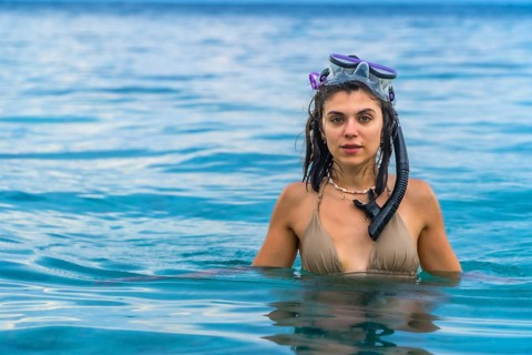 Young woman wearing snorkeling gear, swimming in the crystal clear waters of white beach, moalboal,