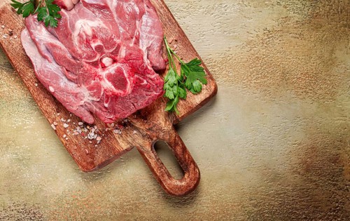 Raw steak, veal neck on the bone, fresh meat, on a cutting board, with spices, top view, without