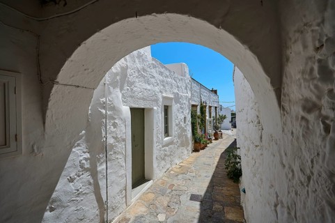 Round arch and whitewashed façade of a historic building with a cobblestone path and potted plants