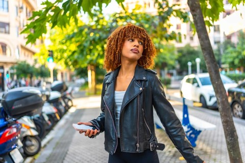 Side view of a beauty millennial latin woman listening to music walking along a city