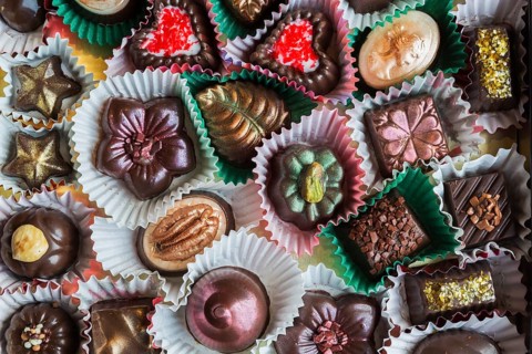 Top view and close-up of hand made mixed flavor fancy fine delicious chocolates in opened chocolate
