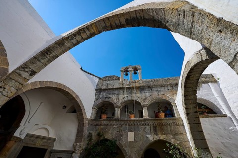 Historic monastery with stone arches and a bell tower under a blue sky, Inside the monastery, Agiou