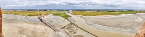 Extensive river landscape with sandbanks and green meadows under a cloudy sky, Le Mont-Saint-Michel