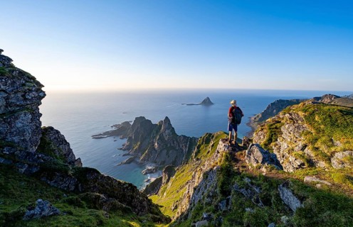 Mountaineer on the summit of Måtind or Måtinden, view of picturesque coastal landscape, rocky coast