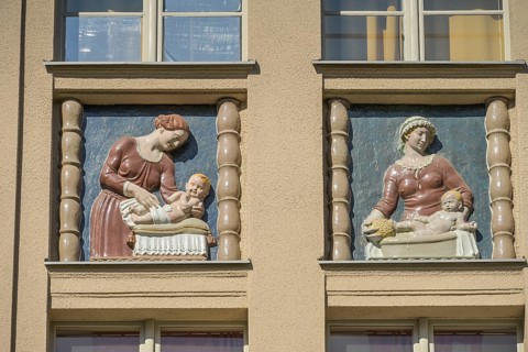 Mothers looking after their babies, relief on an old building, former woman's and children's