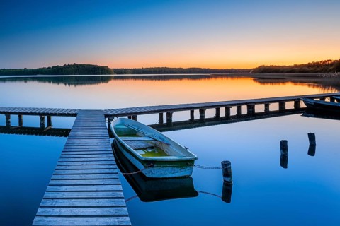 Wooden jetty with rowing boat at dusk, sunset on Lake Schaalsee, Mecklenburg-Western Pomerania,