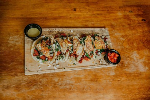 Top view of delicious tacos al pastor with avocado and tomato sauce on wooden table