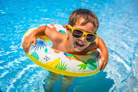 Boy having fun in the swimming pool with a floating rubber ring in summer