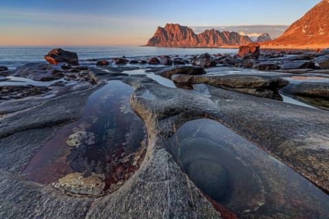 Rocky coast in front of steep mountains in the evening light, winter, the eye, Utakleiv,