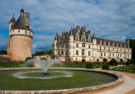 Castle with round tower and fountain in a well-tended garden under a blue sky, Chenonceau Castle,