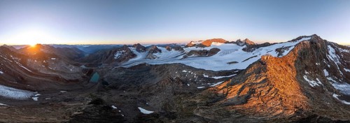 Atmospheric sunrise in a picturesque mountain landscape, alpenglow, aerial view, mountain hut