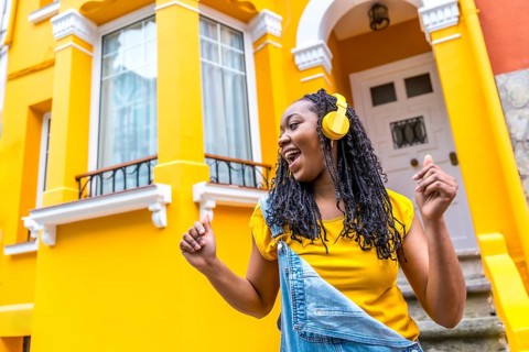 Low angle view photo of a cool african young woman dancing listening to music in the street outside