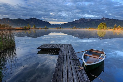 Mountains reflected in lake, jetty and boat, morning light, spring, Loisach-Lake Kochel moor,