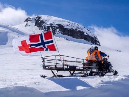 National day 17th May, snowscooter, norwegian flag, near Finse, glacier Hardangerjøkull, Hardanger,