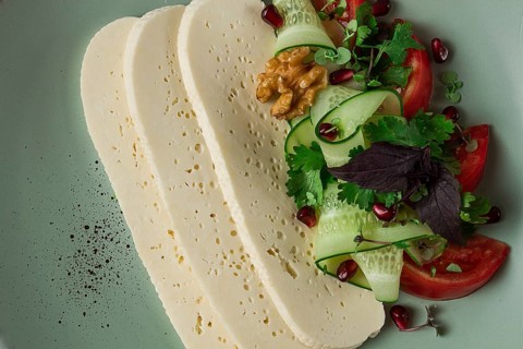 Sliced Imeruli cheese, Georgian cheese, with vegetables, top view, no people