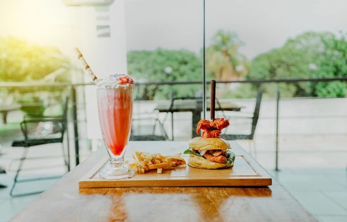 Delicious chicken burger with french fries and strawberry milkshake on restaurant table. Hamburger