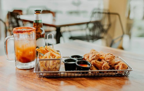 Delicious spicy chicken wings with fries and michelada accompanied by beer served on a restaurant