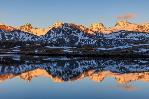 Steep mountains reflected in fjord, evening light, snowy, winter, Moskenesoya, Lofoten, Norway,