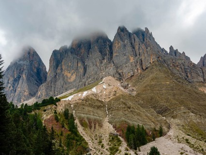 Geisler peaks rise above the rock layers into the cloudy sky, Villnöss Valley, Sass Rigais,