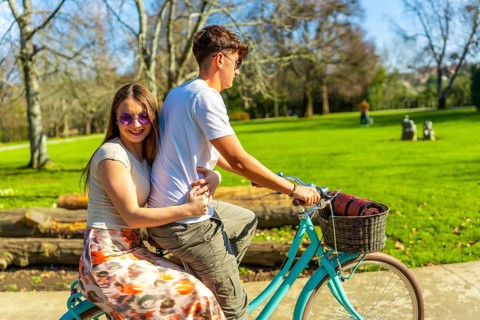 Romantic couple riding a bicycle together on a sunny day, enjoying the lush greenery of a vibrant