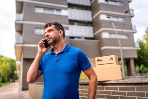 Delivery man talking to the mobile next to parcels to deliver outdoors