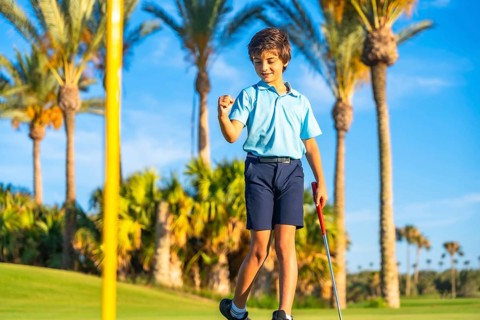 Child celebrating with fist that he makes a put in a green golf course