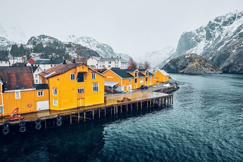 Panorama of Nusfjord authentic fishing village with yellow rorbu houses in Norwegian fjord in