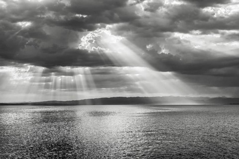 Tyndall effect over Lake Constance, sun rays break through cloudy sky and reflect on the water,