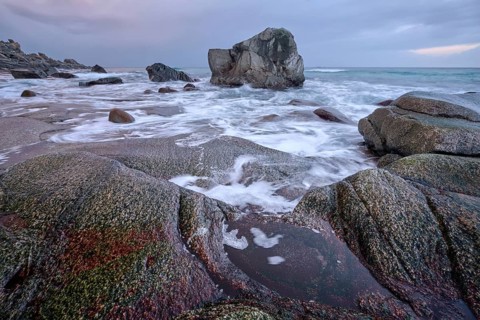 Rocks on beach of fjord of Norwegian sea in winteron sunset. Utakliev beach, Lofoten islands,