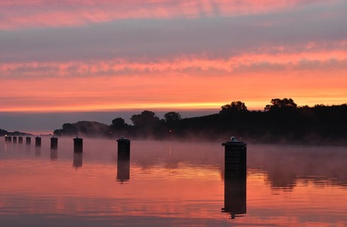 Jetty, dolphins, ship's switch at sunrise and fog on the Kiel Canal, Schleswig-Holstein, Germany,