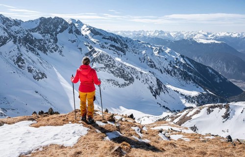 Ski tourer standing next to summit cross, summit of Mitterzeigerkogel in winter, Sellraintal,