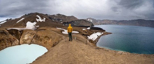 Tourist at the crater rim, crater lake Víti and Öskjuvatn in the crater of Askja volcano, volcanic