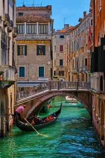 VENICE, ITALY, JULY 19, 2018: Narrow canal between colorful old houses with gondola boat with