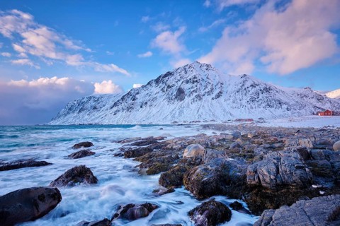 Beach of Norwegian sea on rocky coast in fjord on sunset in winter. Vareid beach, Lofoten islands,
