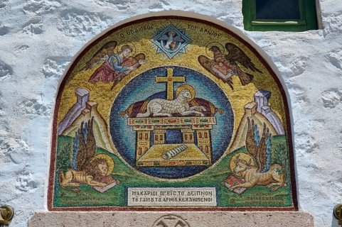 A religious mosaic with Christian symbols and angels, decorating a stone wall in a Catholic church,