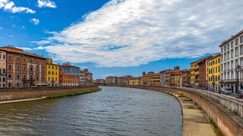 Rows of houses with pastel-coloured facades to the left and right of the River Arno, Pisa, Tuscany,