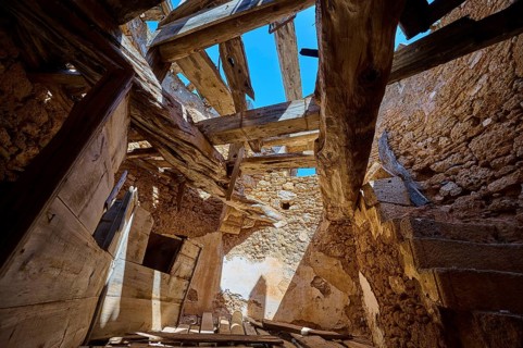 The interior of a crumbling mill with damaged wooden beams and a view of the blue sky, windmill,