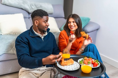 Couple sharing a cozy breakfast at home, enjoying fresh fruit, pastries, and juice, creating a warm