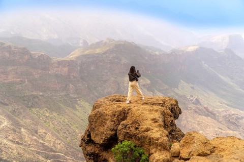 Woman photographing a scenic mountain range in gran canaria, canary islands, enjoying freedom and