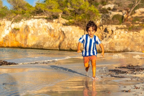 Carefree child enjoying summer holidays, running along the shore of s'amarador beach in mallorca,