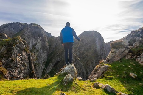 Hiker standing on a rock enjoying the breathtaking landscape of mount penas de aya in oiartzun, a