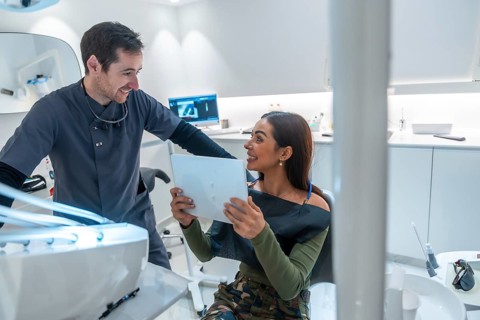 Dentist discussing teeth scan results with a smiling patient, showcasing modern dental technology