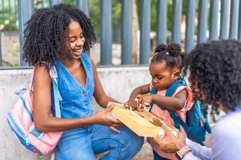 Three generation female african family playing outside school building