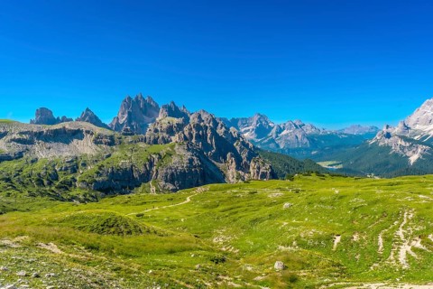 Breathtaking landscape of tre cime di lavaredo peaks towering above lush green meadows in the
