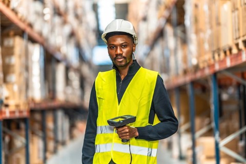 Frontal portrait of an african man using scan to do inventory in a warehouse