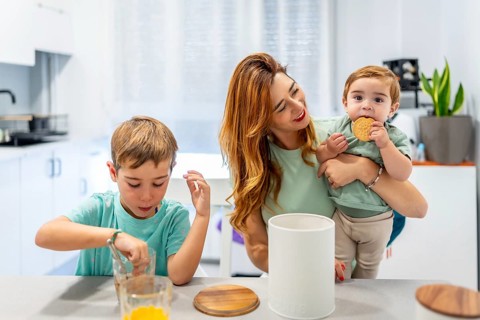 Schoolboy enjoying breakfast with his family at home dipping the cookies in the milk