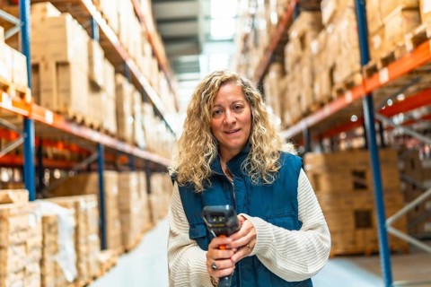 Frontal view of a caucasian blonde woman scanning packages in a distribution warehouse