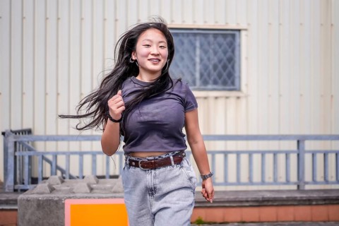 Happy asian young woman dancing urban music in an outdoor industrial space