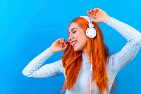 Redhead woman in studio photography smiling dancing on a blue background